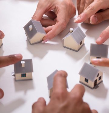 Group,Of,People,Touching,Miniature,House,On,White,Background